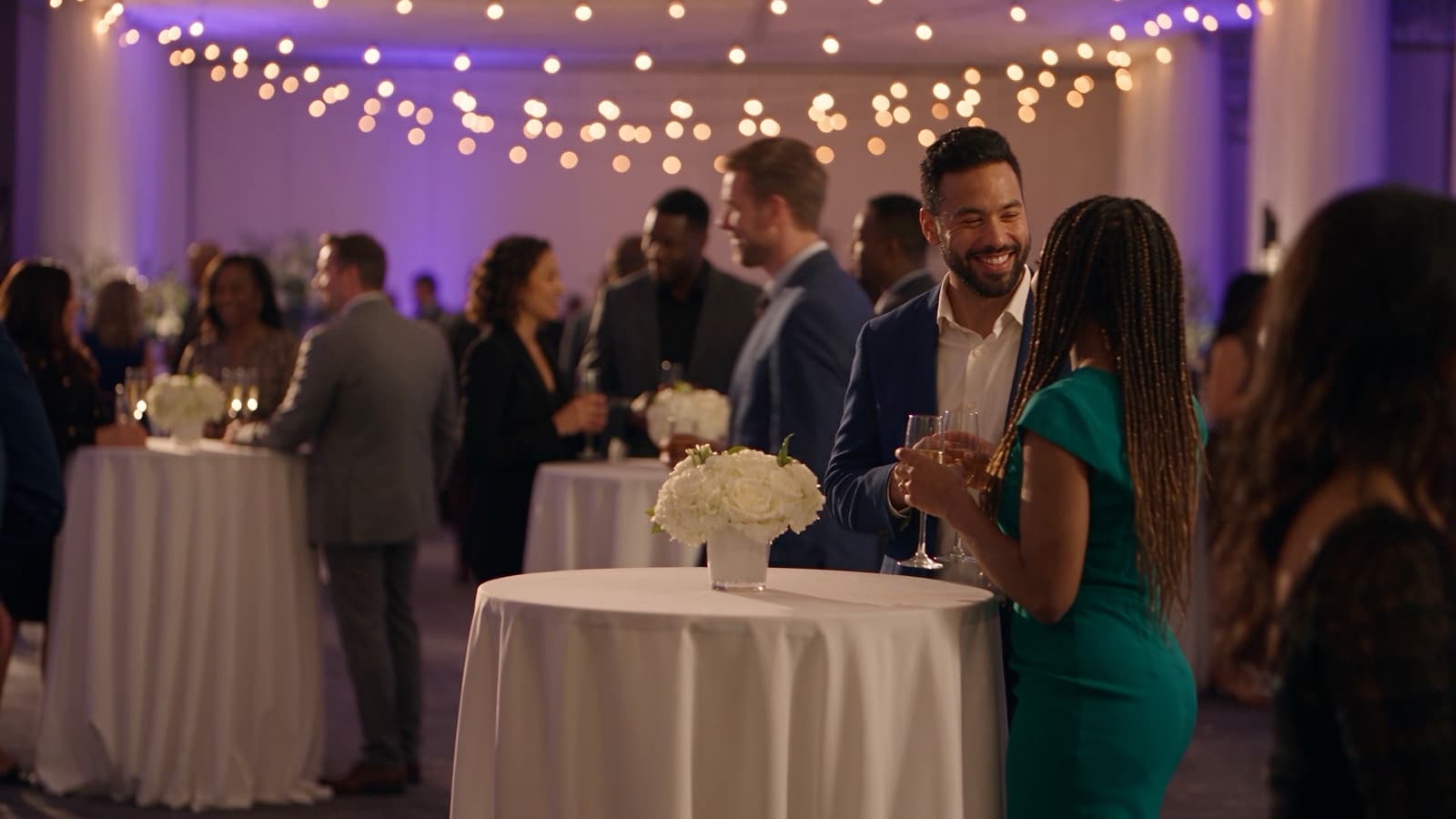 Diverse professionals networking at a corporate evening reception with purple uplighting